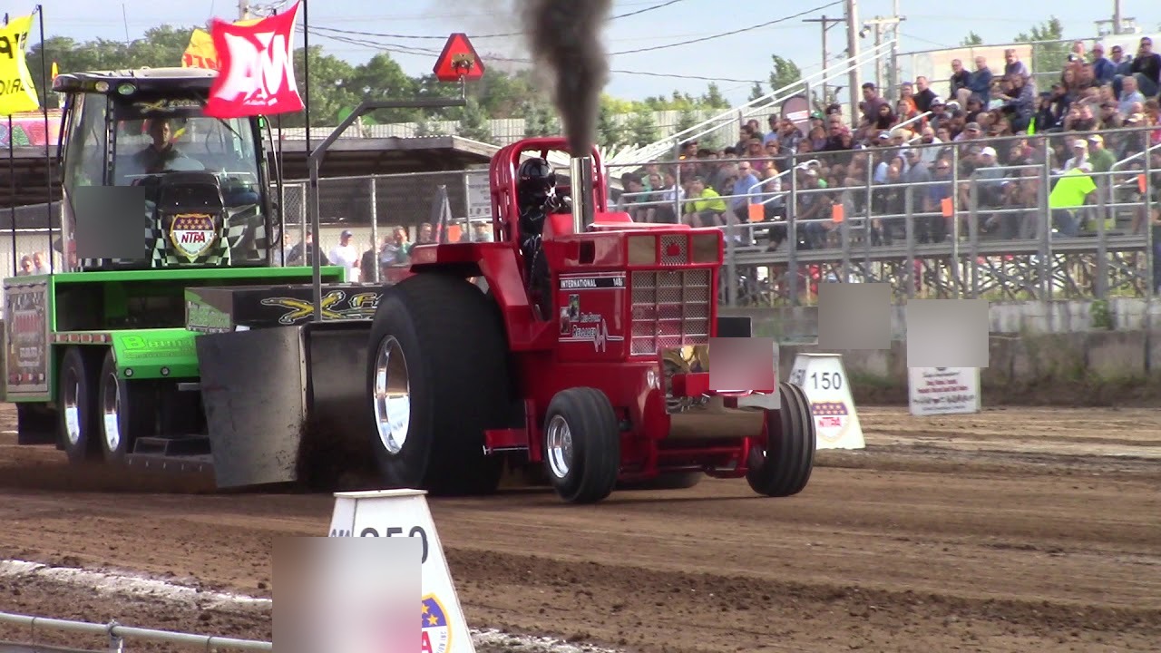 Red tractor pulling at a dirt track